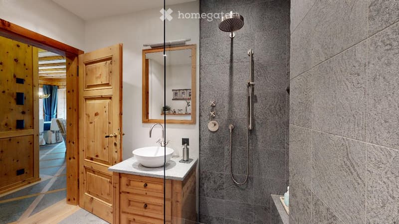 Modern bathroom with white sink, wooden vanity, grey tiles, and modern shower