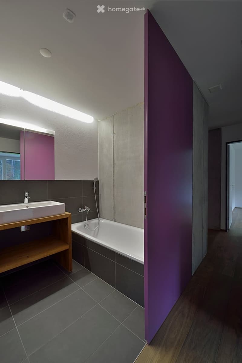 Bathroom with white bathtub, sink, wooden shelf, tiled floor, mirror, and purple wall