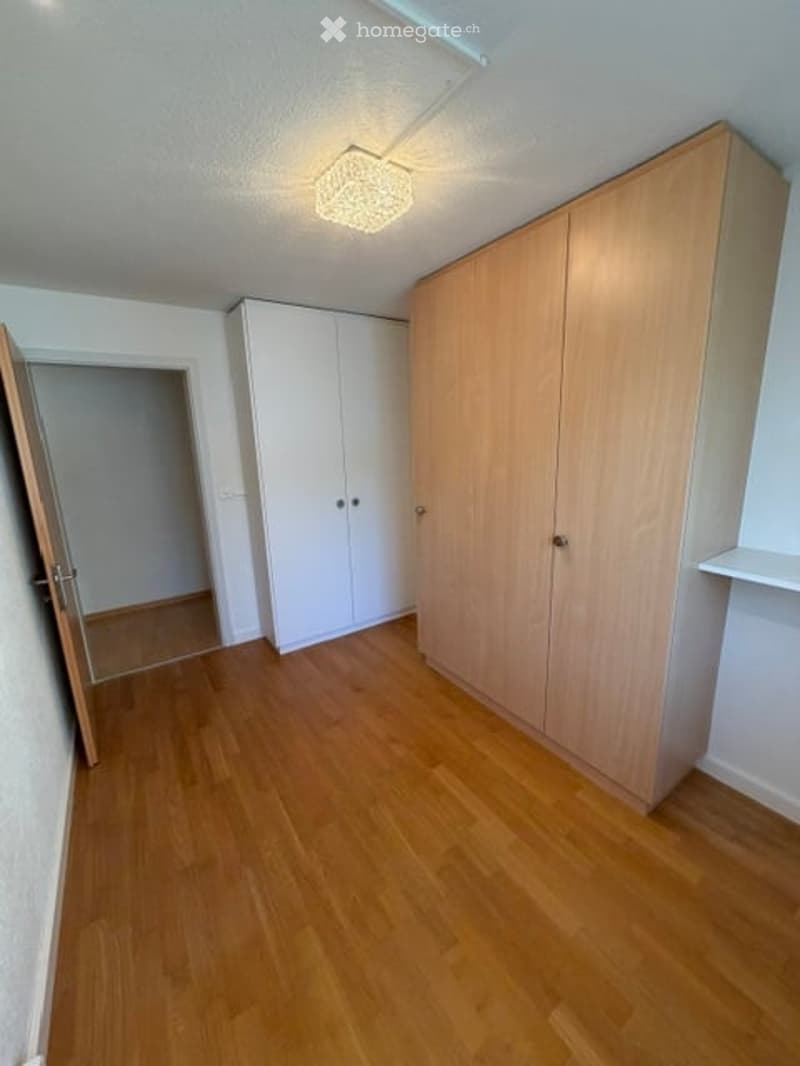 Empty room with wooden flooring, white walls, and built-in wardrobes. No furniture or equipment present.