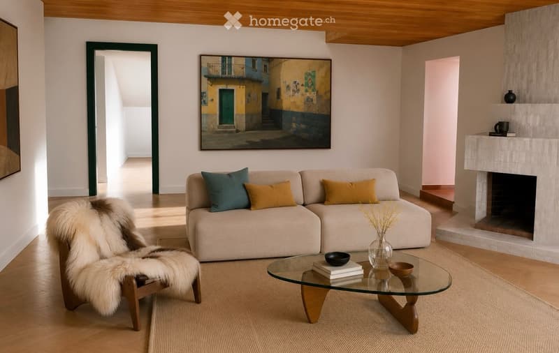 Modern living room with a white sofa, glass coffee table, fur chair, fireplace, and artwork on the wall.