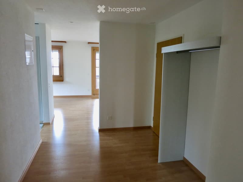 Empty hallway with wooden flooring, white walls, and two doors leading to other rooms.