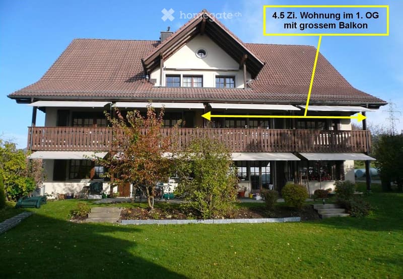 Two-story house with a red-tiled roof, large balcony on the first floor, and well-maintained garden.