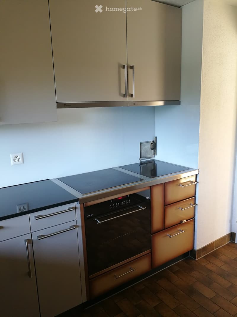Modern kitchen with light-colored cabinets, stainless steel appliances, and a tiled floor.
