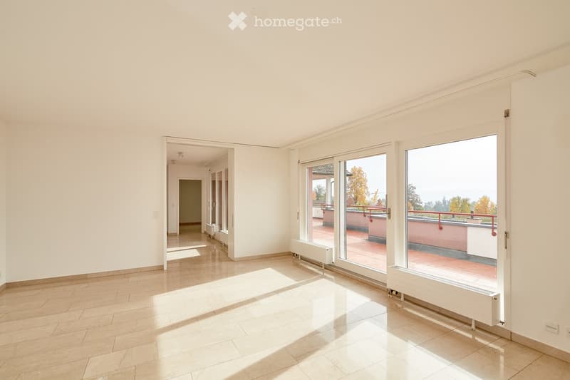 Empty room with white walls, tiled floor, large sliding glass doors leading to a balcony, and radiators visible along the walls.