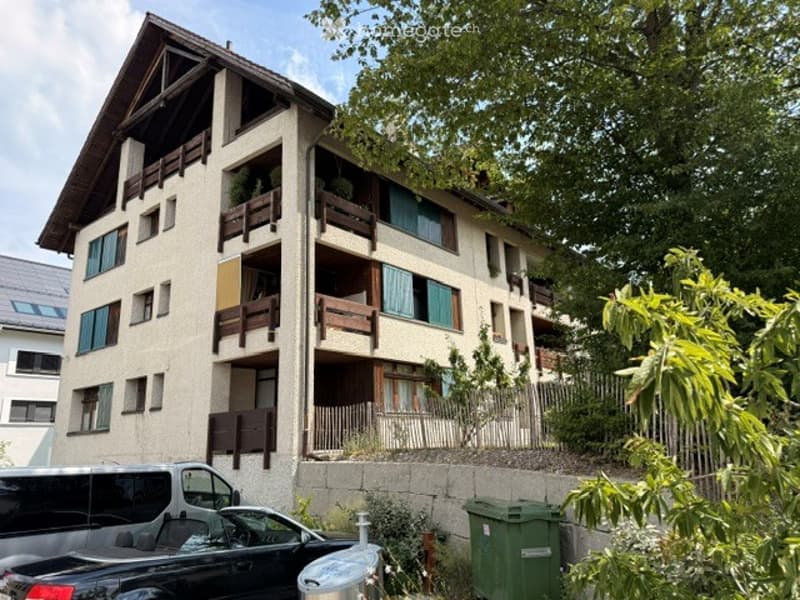 Multi-story residential building with balconies, large windows, and a mix of modern and traditional architectural elements.