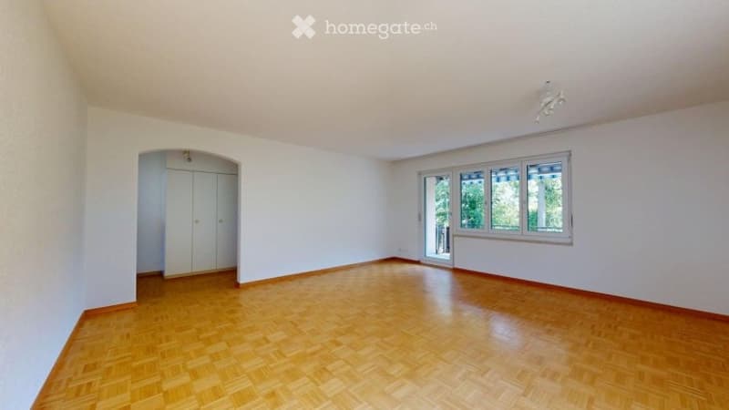 Empty room with light-colored walls, wooden flooring, and large windows. No furniture or equipment is present.