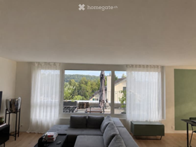 Modern living room with large windows, grey sectional sofa, coffee table, floor lamp, and a small table near the window.