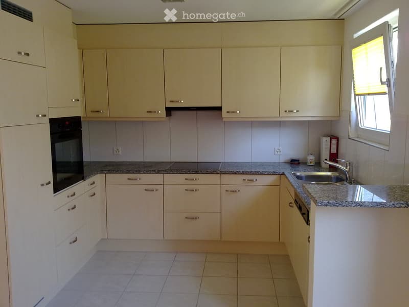 Modern kitchen with light-colored cabinets, granite countertop, stainless steel sink, and built-in oven.