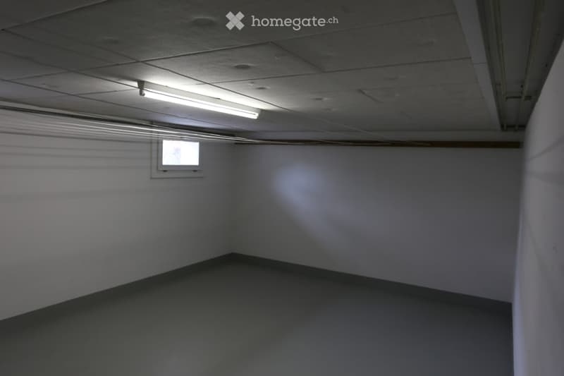 Empty room with white walls, grey floor, and a small window. No furniture or equipment present.
