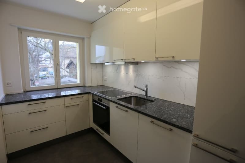 Modern kitchen with white cabinets, granite countertops, and stainless steel sink and faucet.