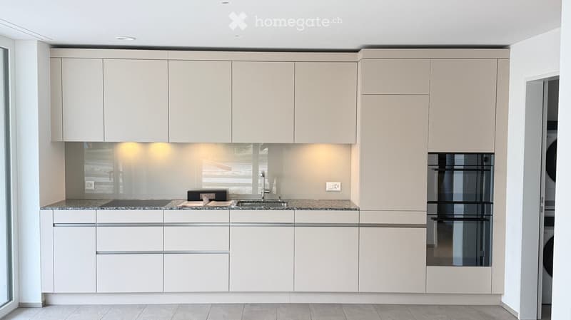 Modern kitchen with white cabinets, granite countertop, sink, and built-in oven.