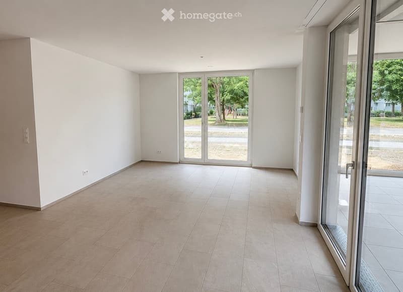 Empty room with tiled floor, white walls, and large glass sliding doors leading to an outdoor area.