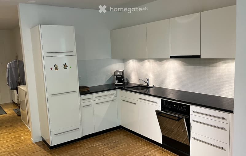Modern kitchen with white cabinets, stainless steel appliances, and a black countertop.