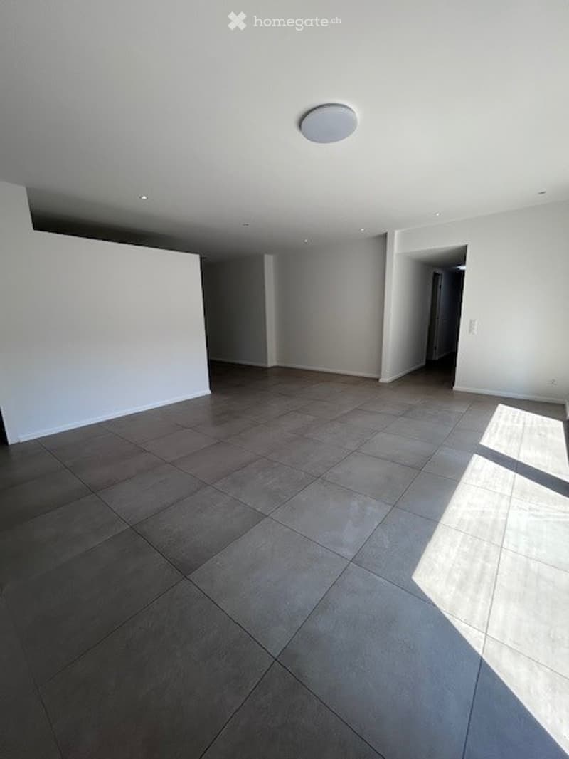Empty room with tiled floor and white walls, featuring a recessed ceiling light and an open doorway leading to another space.