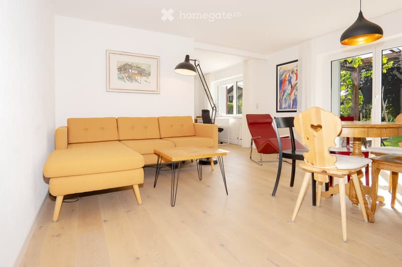 living room with sofa, coffee table, chairs, dining table, picture frames, pendant lamp, and a glass door with balcony
