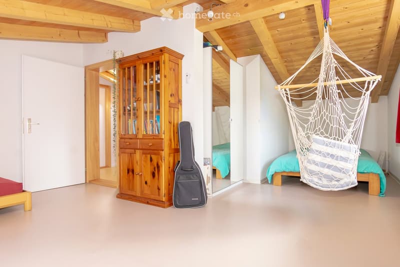 empty bedroom with hanging chair, small cabinet, guitar case, hardwood floors