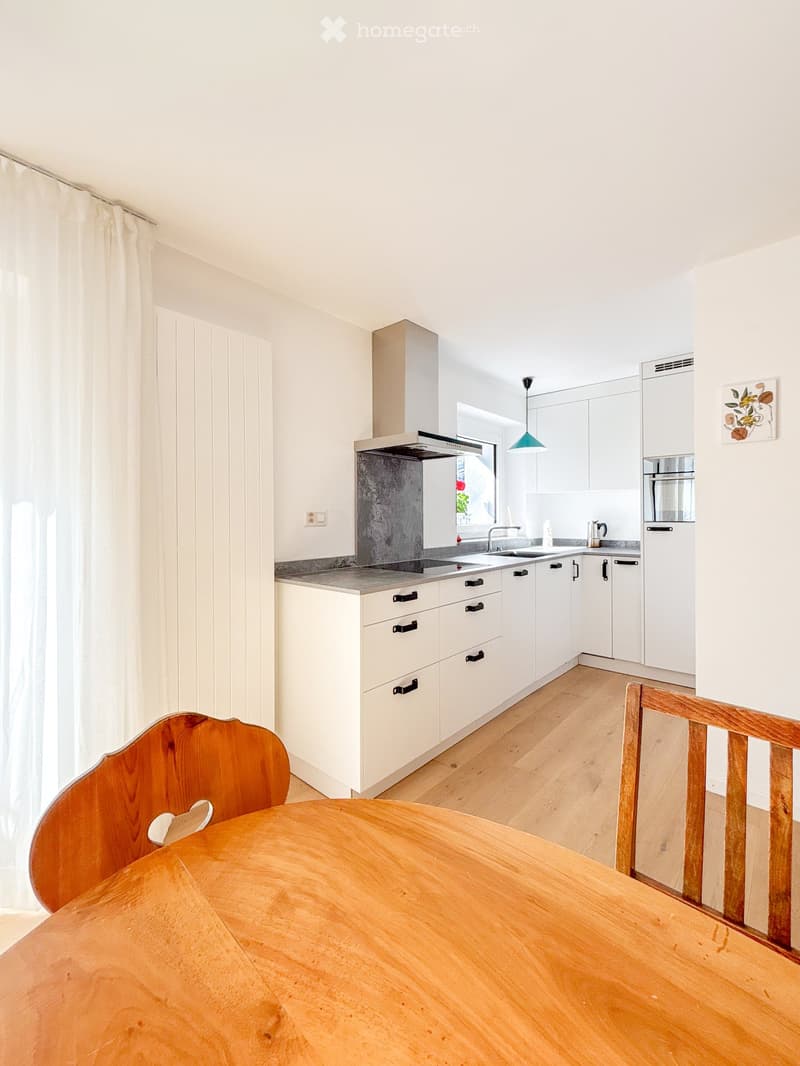 modern kitchen with white cabinets, wooden floor, kitchen island, and a round wooden table