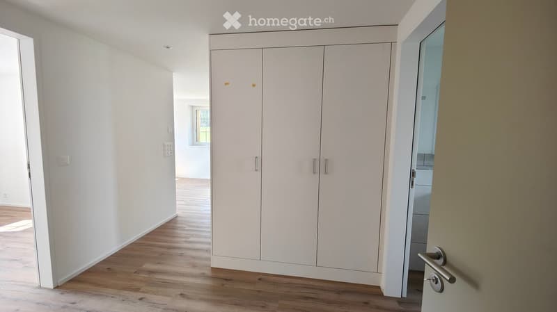 Empty room with light-colored walls, wooden flooring, and a large built-in wardrobe. The room is unfurnished and has a neutral, minimalist design.