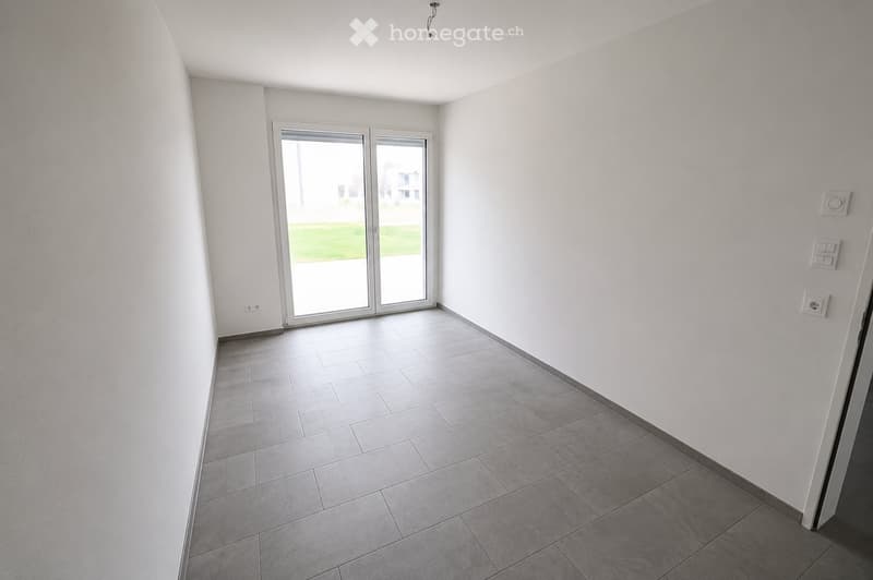 Empty room with white walls, tiled floor, and large sliding glass door leading to an outdoor area.