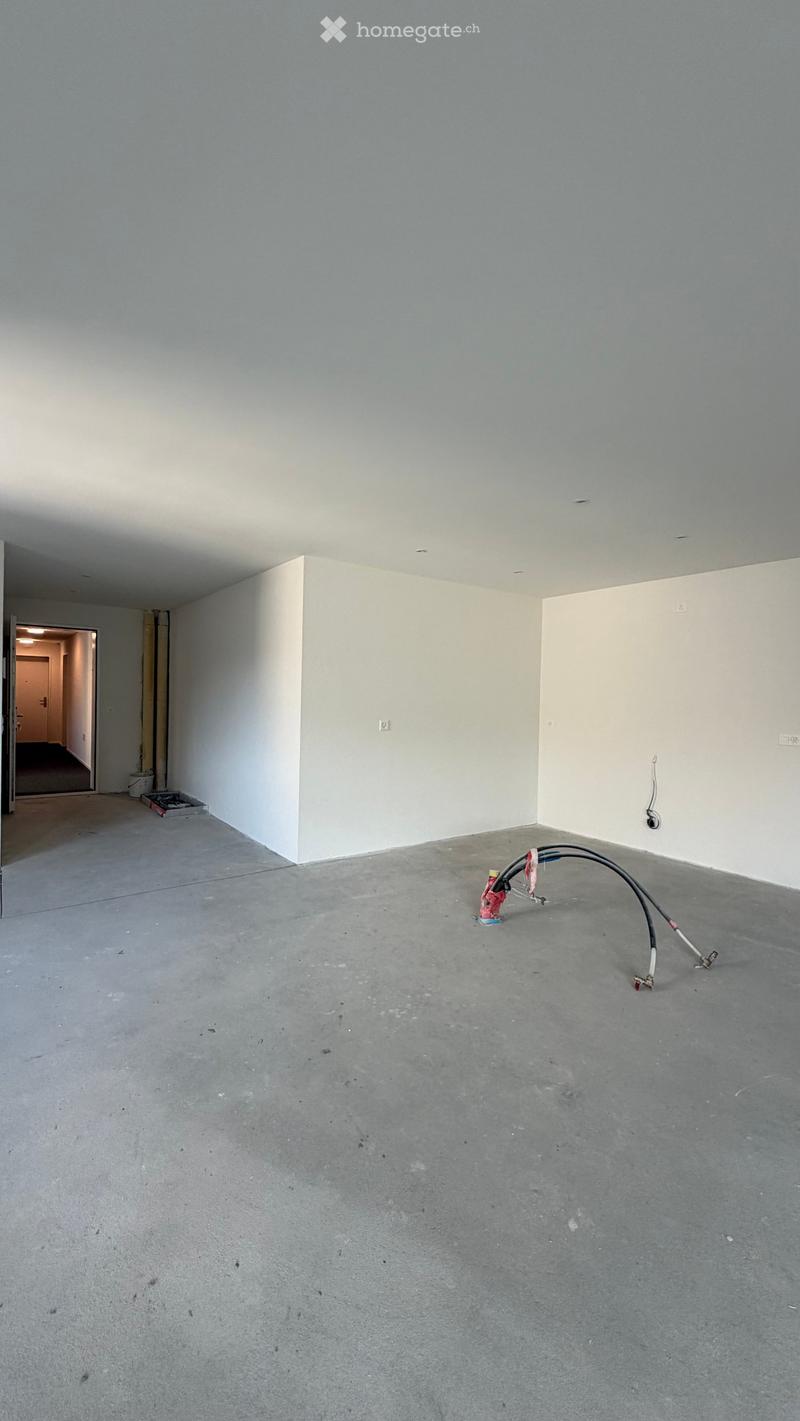 Empty room with bare walls and concrete floor, featuring a doorway leading to another area.