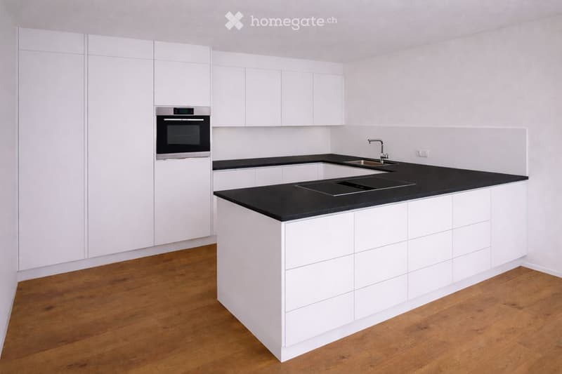 modern kitchen with white cabinets, black countertops, stainless steel oven, sink, faucet, wooden floor