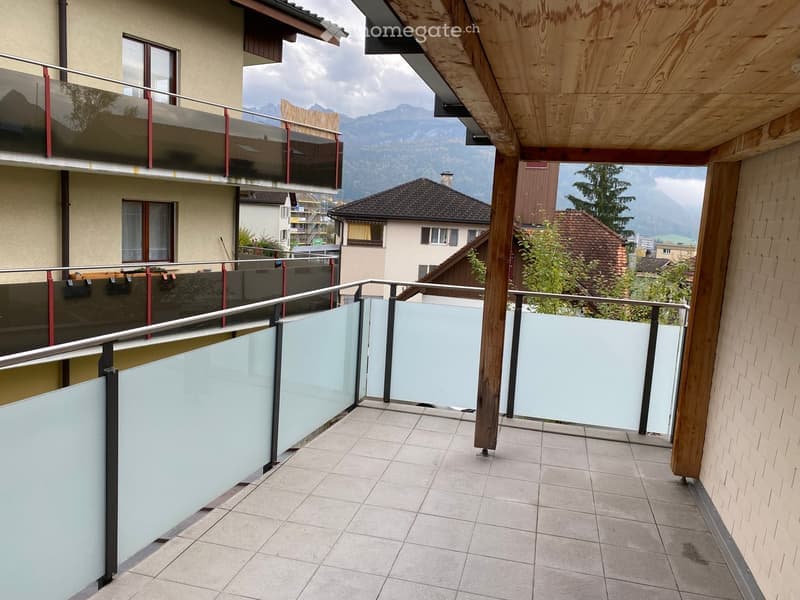 Balcony with tiled floor, glass railing, and a scenic mountain view in the background.