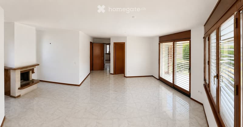 Bright hallway with tiled floor, white walls, fireplace on left, sliding glass doors leading outside on right.