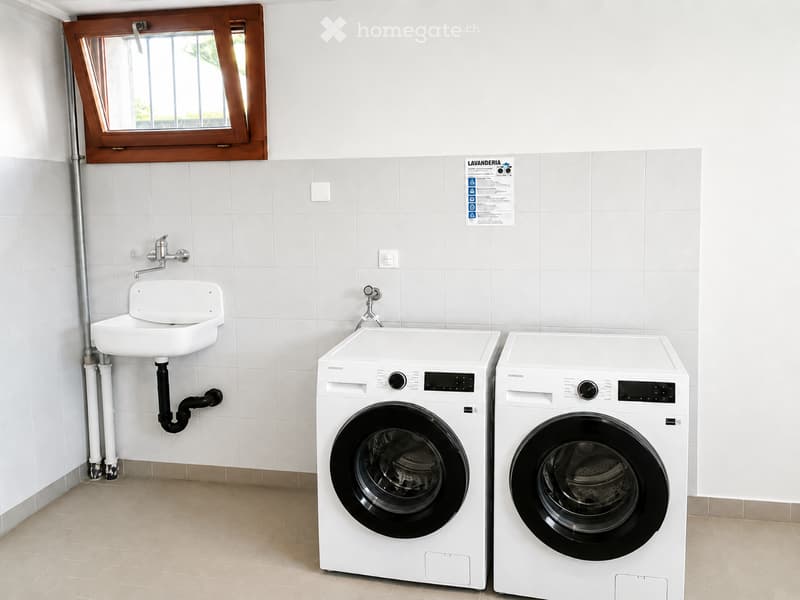 Modern bathroom with white tiled walls, a small sink, and two Samsung washing machines and dryers.