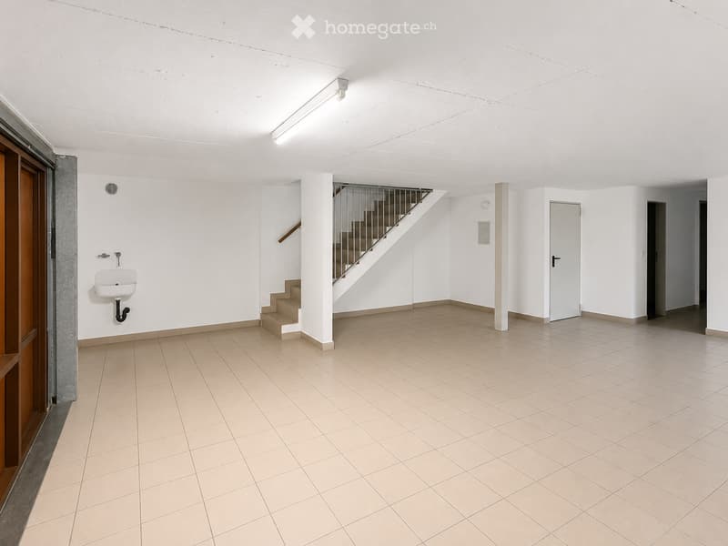 Empty room with tiled floor, white walls, staircase leading upwards, and a small sink in the corner.