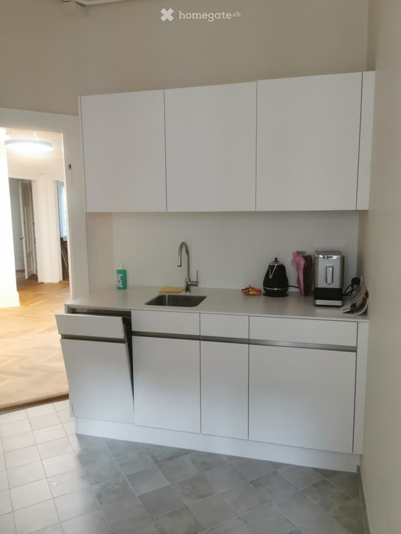 modern kitchen with white cabinets, stainless steel sink, faucet, coffee machine, kettle, and dishwasher