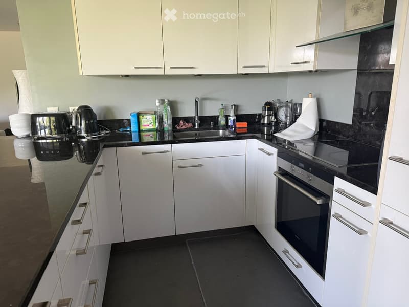 Modern kitchen with white cabinets, black countertops, and stainless steel appliances including an oven, toaster, and sink.