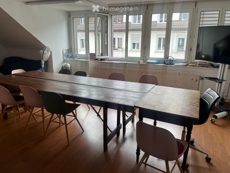 large wooden table, multiple chairs, large windows, fan, television