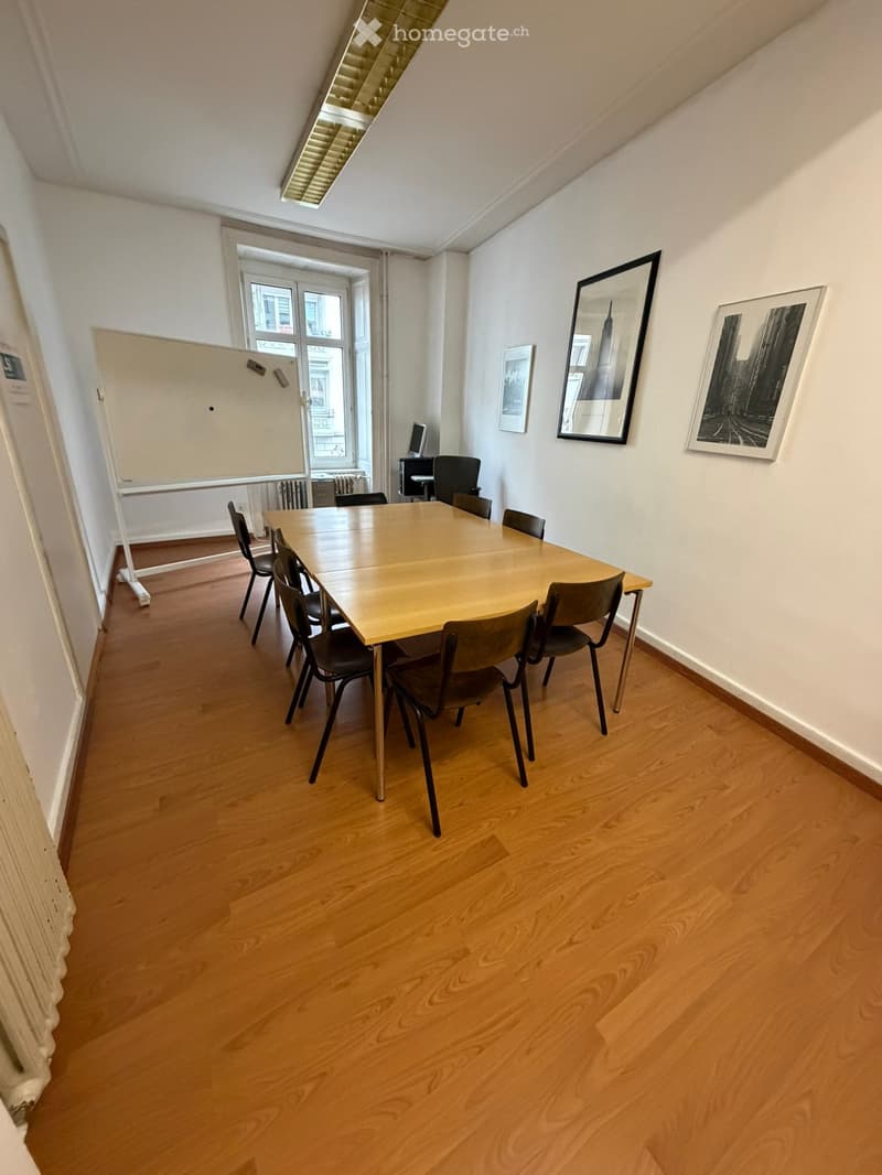 large wooden table, black chairs, whiteboard, framed art, radiators, radiators