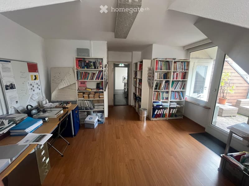 wooden floor, white walls, multiple bookshelves filled with books, open door, trash can, desk with books and papers, chair