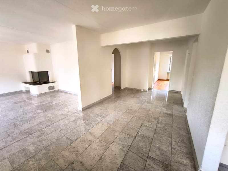 Empty hallway with tiled floor, white walls, and an arched doorway leading to another room.