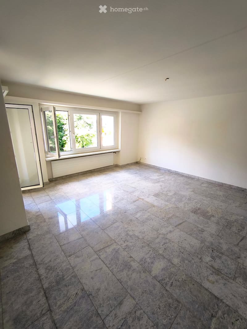 Empty room with large windows, marble flooring, and white walls.