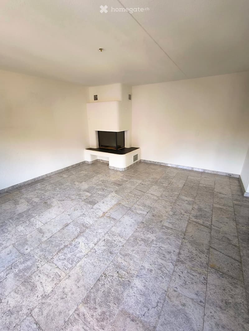 Empty room with light-colored walls, a built-in fireplace, and a tiled floor.