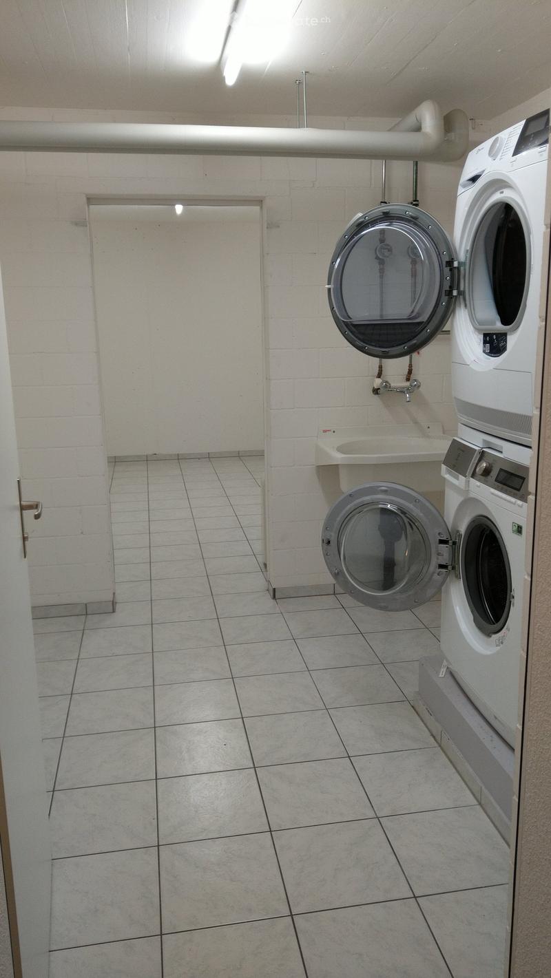 Clean, tiled bathroom with a washing machine and a sink.