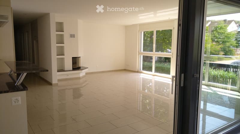 Empty room with tiled floor, white walls, built-in shelving unit, and large windows with a sliding glass door leading outside.