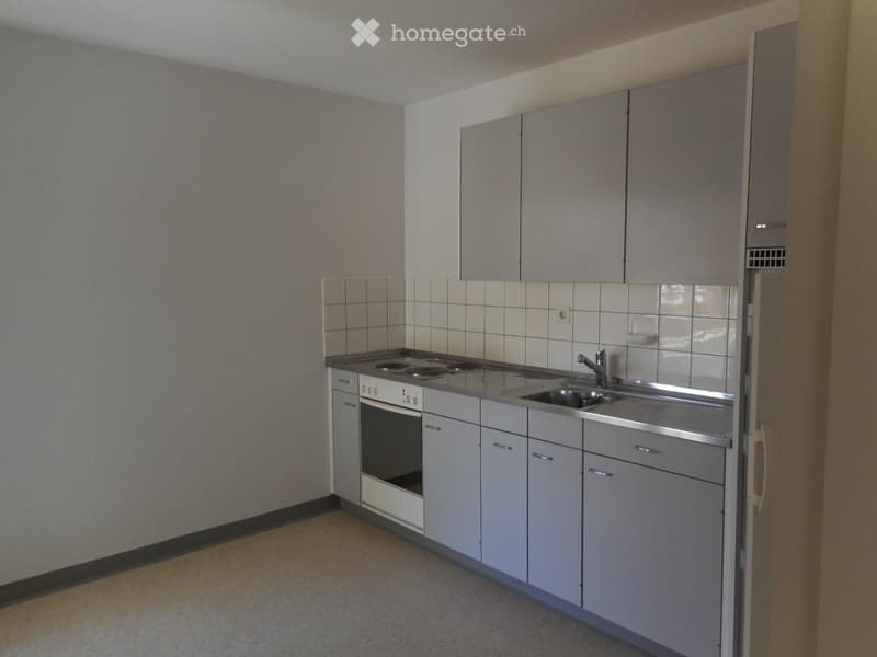 Modern kitchen with white cabinets, stainless steel sink, and electric stove.