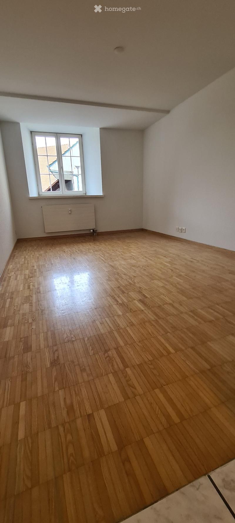 Empty room, wooden floor, white walls, radiator, windows