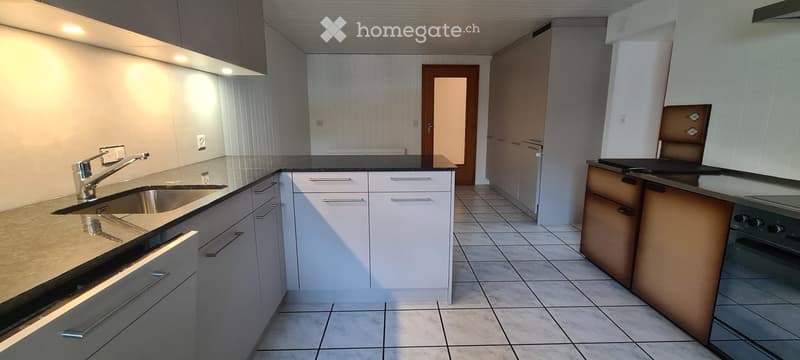 Modern kitchen with granite countertop, gas oven, sink, cabinets, stainless steel appliances, and tile flooring.