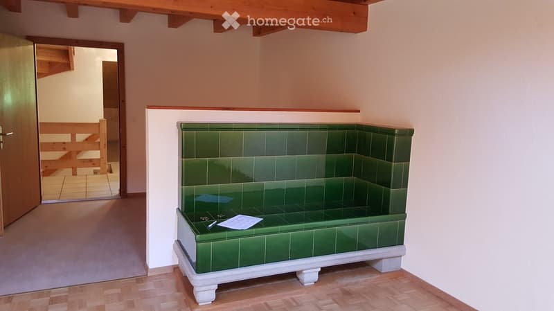 Hallway with wooden flooring, green tiled bench, and a wooden staircase in the background.