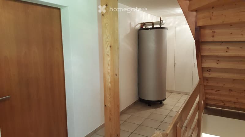 Utility room with tiled floor, wooden walls, and a water heater. No furniture or personal items visible.