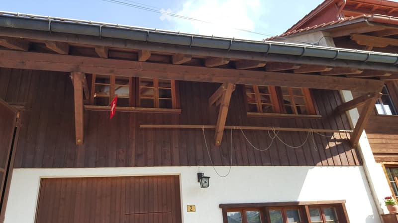 Traditional wooden house with exposed beams, wooden balconies, and a garage entrance.