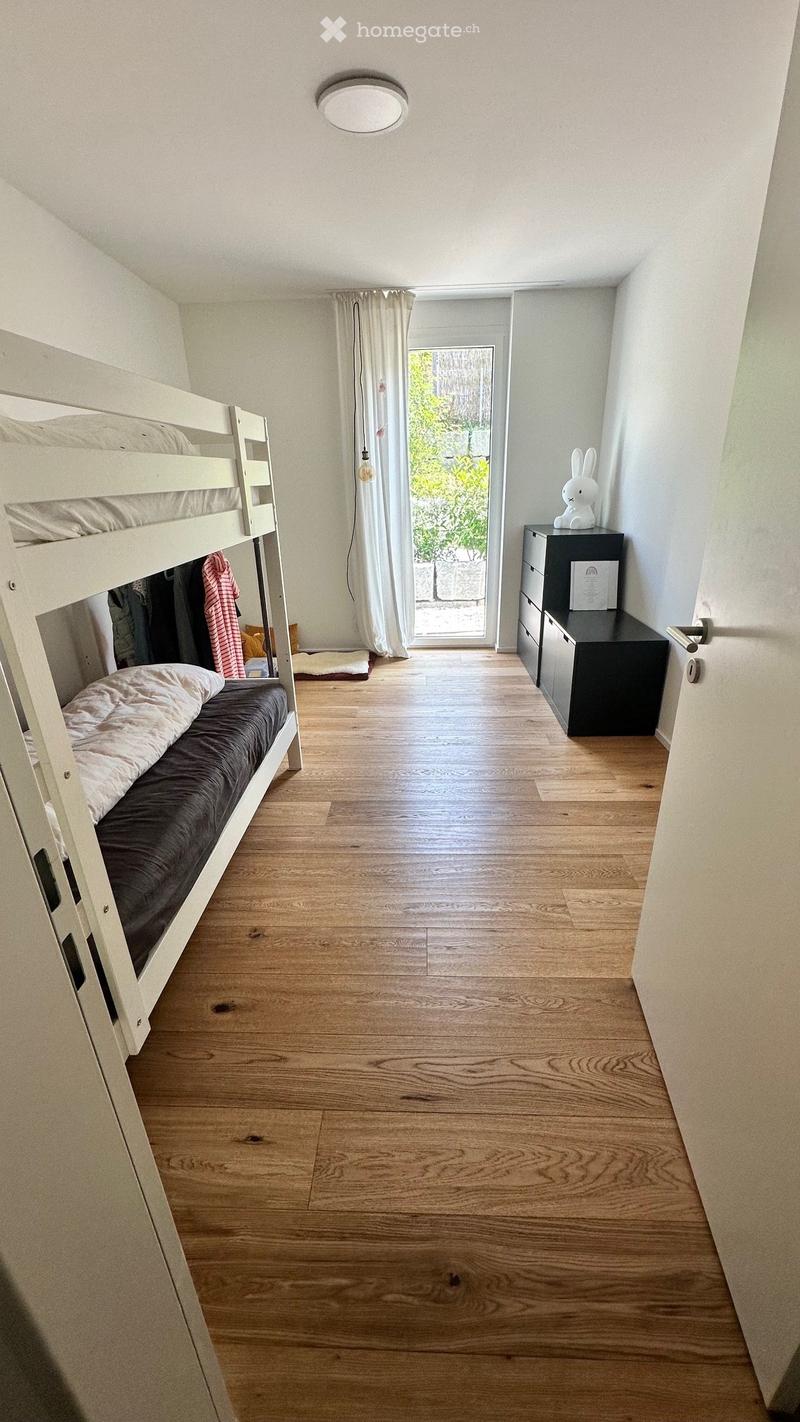 Cozy bedroom with wooden floor, bunk bed, nightstand, and a small statue on top.