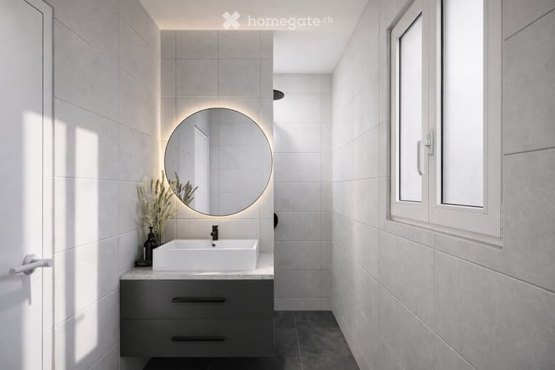Modern bathroom with a white sink, dark grey cabinet, round mirror, and vase with dried flowers on the counter.