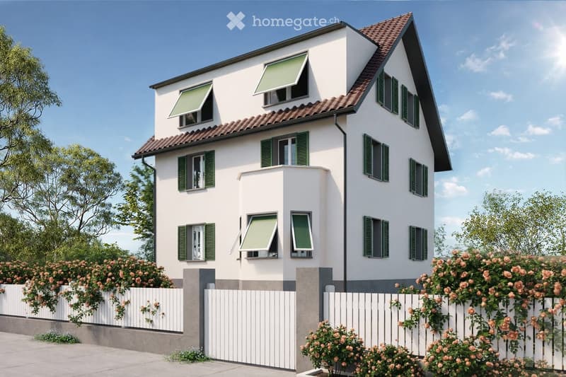 Two-story house with white exterior, green shutters, and a red-tiled roof. Features multiple windows, a small balcony, and a white picket fence with rose bushes.