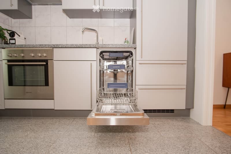 modern kitchen with white cabinets, stainless steel appliances, open dishwasher