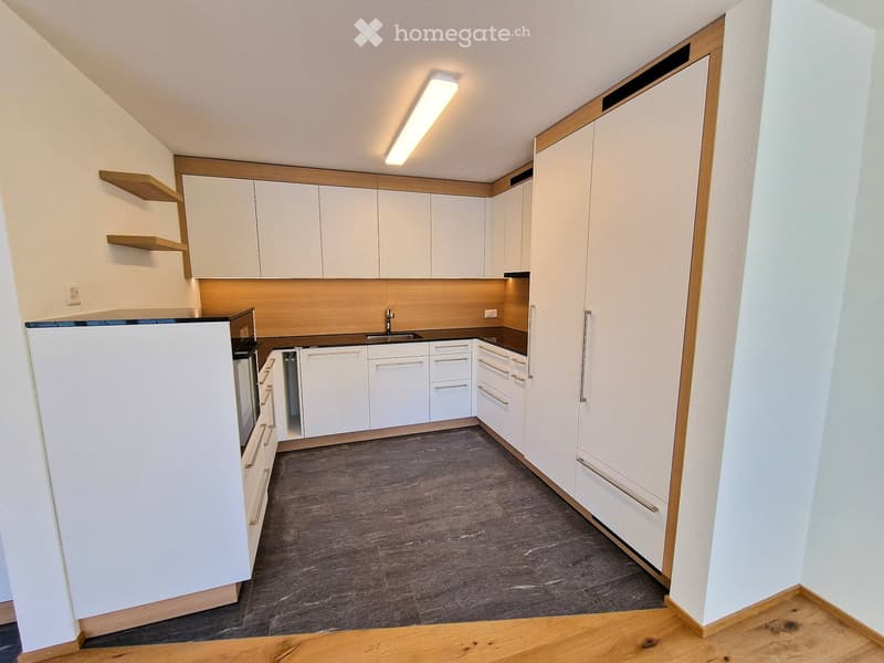 Modern kitchen with white cabinets, a refrigerator, oven, sink, and wooden shelves.